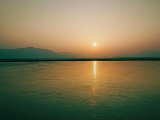 Fototapeta premium A breathtaking sunset over a tranquil river reflecting golden light with silhouette mountains