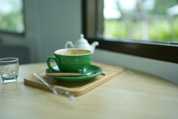 Empty green cup after drink coffee on a wooden table near window. The concept for ending break or something else.