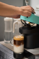 Man using capsule coffee machine with espresso cup. Nespresso is worldwide leader company with coffe machines and capsules.