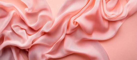 Obraz premium Silk fabric draped elegantly in soft pink tones with smooth texture and subtle sheen on a light background with Copy Space