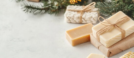 Handmade natural soaps wrapped in kraft paper with twine on a light surface decorated with pine branches and festive lights Copy Space