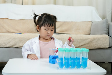 Asian Girls learn before going to school, conducting an experiment in home lab with test tubes and...