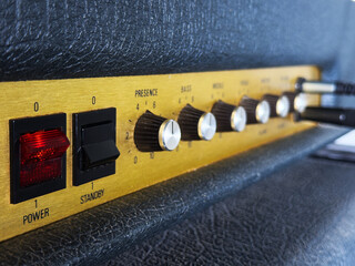 Closeup focus on the power and standby switches on a generic vintage valve amplifier, covered in...
