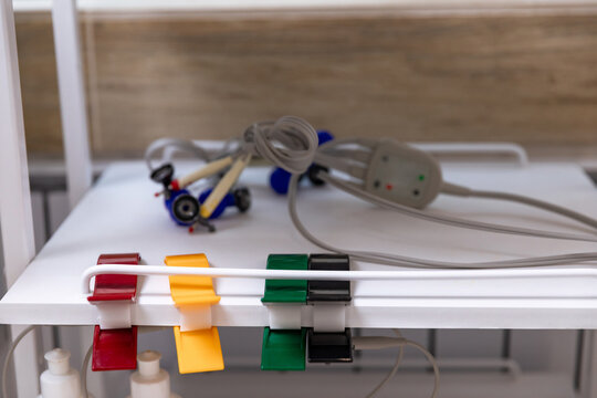 Electrocardiogram equipment for making cardiogram test of patient who is attached with vacuum sensors to the machine near coach in medical office room. Healthcare concept