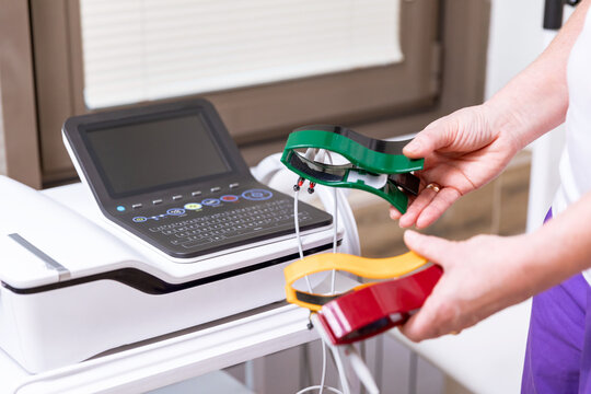Cardiologist with electrocardiogram equipment is making cardiogram test of patient who is attached with vacuum sensors to the machine. Healthcare concept