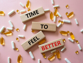 Time to feel better symbol. Concept word Time to feel better on wooden blocks. Beautiful pink background with pills. Health concept. Copy space