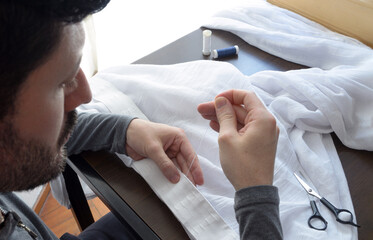 Hombre cosiendo a mano con técnica de punto sobrehilado. Costura de tela con aguja e hilo.