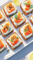 Gourmet open faced salmon sandwiches with cream cheese, capers, dill on rye, served alongside bright lemon wedges on crisp white platter