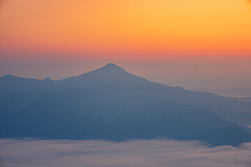 The stunning view from a tourist's standpoint as they go down a hill on a foggy trail with a hill...