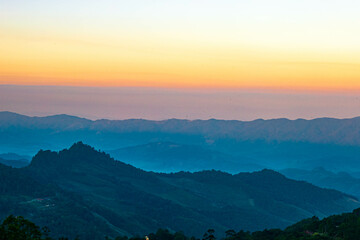 The stunning view from a tourist's standpoint as they go down a hill on a foggy trail with a hill...