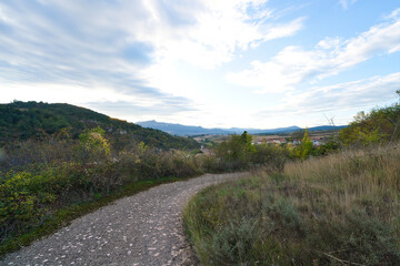 Path between blackthorn bushes with the village of Salinas de Añana in the background