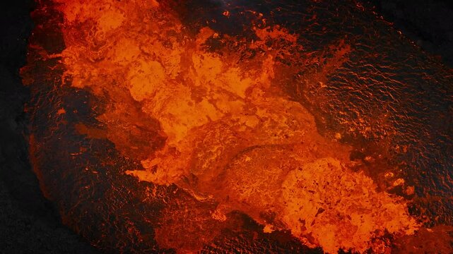 Unique close up view of red hot lava exploding, boiling, and bubbling in the volcano crater, drone shot. Volcanic eruption, natural hazard, and disaster concepts.