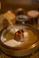 Preparation of Turkish coffee in the cezve in the sand.