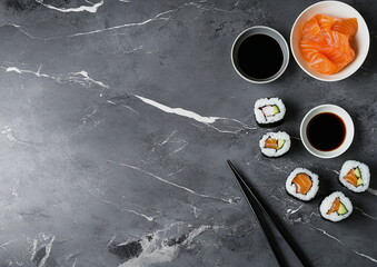 Naklejka premium Sushi rolls and nigiri on a stone-textured background, top view. A high-resolution food image showcasing traditional Japanese sushi, ideal for restaurant menus and culinary visuals.