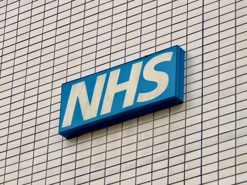 London, UK - October 30, 2024: Blue and white NHS sign on the wall of a hospital in London. 