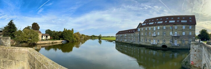 A scenic panoramic view of the historic Riverside Mill building overlooking the River Great Ouse at Huntingdon, Cambridgeshire, UK. 