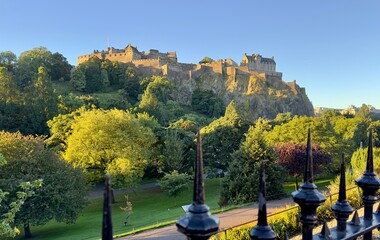A view of Edinburgh Castle seen across Princes Street Gardens under a clear blue sky, Scotland. 