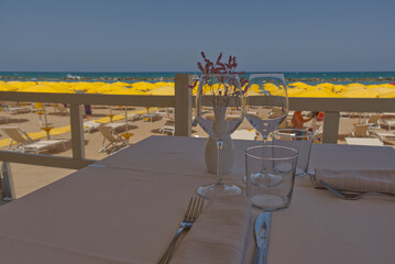 Fototapeta premium glasses with wine for lunch with blurry beach umbrellas in the background
