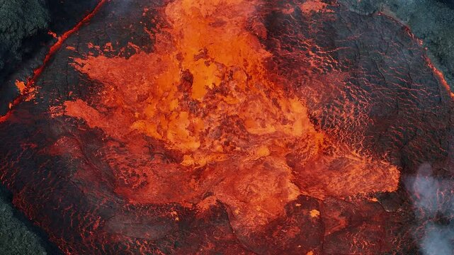 close up top down view of red hot lava exploding, boiling, and bubbling in the volcano crater, drone shot. Volcanic eruption, natural hazard, and disaster concepts.
