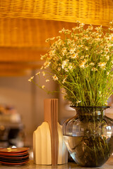 Cutlery, a napkin holder and a vase with a flower on a wooden table