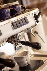 Closeup of pump driven espresso machine and portafilter brewing by forcing pressurized water through puck.