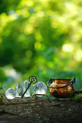 witch cauldron with vintage key, quartz crystal balls and towers in forest, natural background....