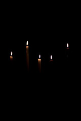 Silhouettes of lighted candles on a dark background.