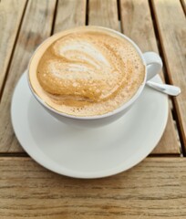 Cup of Cappuccino with Latte Art Heart Shape on Wooden Table