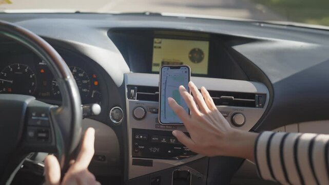 Female passenger zooming in on map displayed on smartphone attached to dashboard in moving car. Woman adjusting navigation app while traveling in unknown area. Giving precise directions.