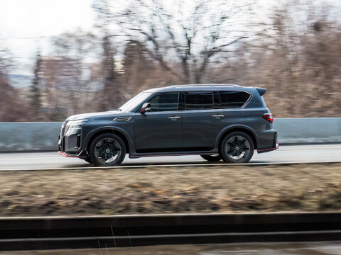 Nissan Armada SUV vehicle on country road. Fast moving gray car accelerating with low-emission. Compliance with speed limits on the road