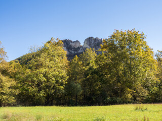 Summit of Seneca Rocks, West Virginia, framed by trees in fall colors, a meadow and a blue sky