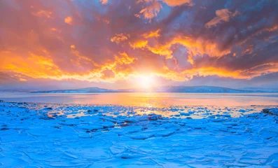 Fotobehang Panoramic view at fjord with coast of the Norwegian Sea in the background snowy mountains Arctic Circle at sunset - As a result of melting snow, freezing of the water mixed with the sea - Norway © muratart