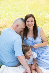 Fototapeta premium Mom, dad and daughter having fun on a picnic. Family vacation in nature