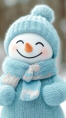 A cheerful snowman wearing a cozy blue knitted hat and scarf with a carrot nose, set against a soft-focus winter background.