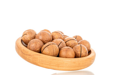 Several macadamia nuts on a wooden plate, close-up, isolated on a white background.
