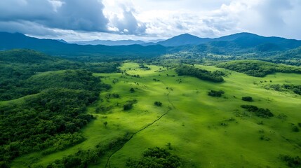 Obraz premium Expansive Green Meadow with Mountains Under Cloudy Sky Scenic Pastoral View : Generative AI