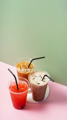Three takeaway glasses of coloured summer drinks with ice. Cocktails on colored background