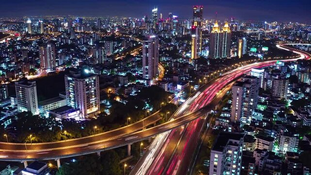 A breathtaking 4K ultra-HD aerial stock video capturing Mumbai&rsquo;s vibrant nighttime skyline, featuring a sprawling highway illuminated by mesmerizing streaks of red and white light trails from moving v