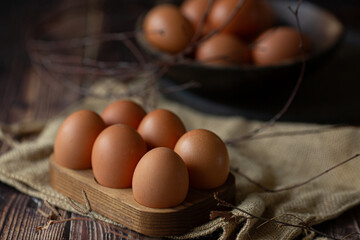 Brown chicken eggs in wooden base on dark background, perfect for easter, natural light  