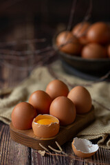 Brown chicken eggs in wooden base on dark background, perfect for easter, natural light  
