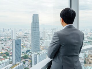 Fototapeta premium A businessman in a suit stands in a high-rise, gazing at a sprawling urban skyline through a large window, exhibiting a serene and contemplative mood.