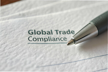 The image features a close-up of a pen resting on a document titled "Global Trade Compliance," emphasizing the importance of trade regulations.