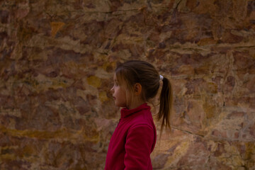 Young girl observing prehistoric cave paintings depicting animals and symbols, experiencing history and art during a museum visit, fostering curiosity and learning.
