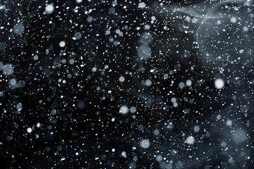 Obraz premium Snowflakes falling gently against a dark, blurred background, creating a serene winter atmosphere.