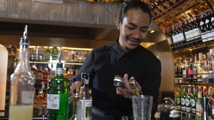 Asian bartender pouring mixed cocktail juice liqueur all ingredient into sliver shaker alcohol drink, making special advertisement creative tasty, focused refreshing showcase at bar luxury. Vinosity.