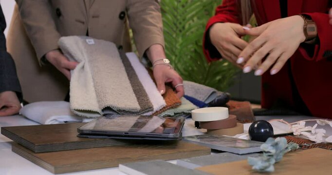 Interior design professionals collaborating at table, reviewing wood, fabric, and tile samples while planning comprehensive renovation strategy. Selection of materials for interior design