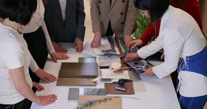 Professional interior designers reviewing renovation plans on tablet, analyzing material samples and color palettes during collaborative client consultation. Concept selection of materials for repair