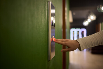 Pressing the elevator button in contemporary high rise buildings signifies modern urban convenience