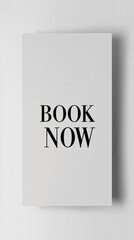 Book Now Announcement: A minimalist, aesthetically pleasing vertical shot featuring a card inscribed with "BOOK NOW," poised against a refined backdrop, perfect for promoting booking or reservations.