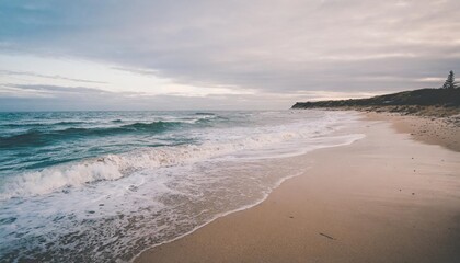 Obraz premium Empty Beach Captured at Sunset with Waves Crashing on Shore